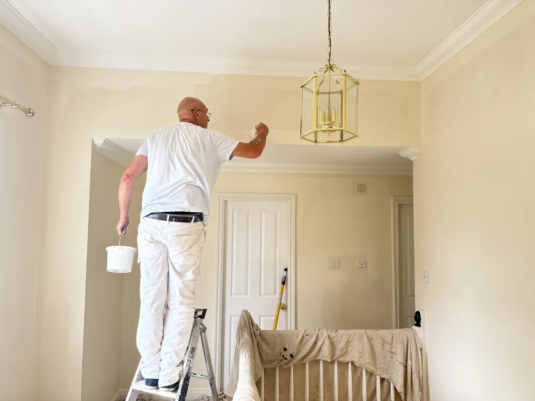 Decorator cutting in around a landing wall with the staircase protected