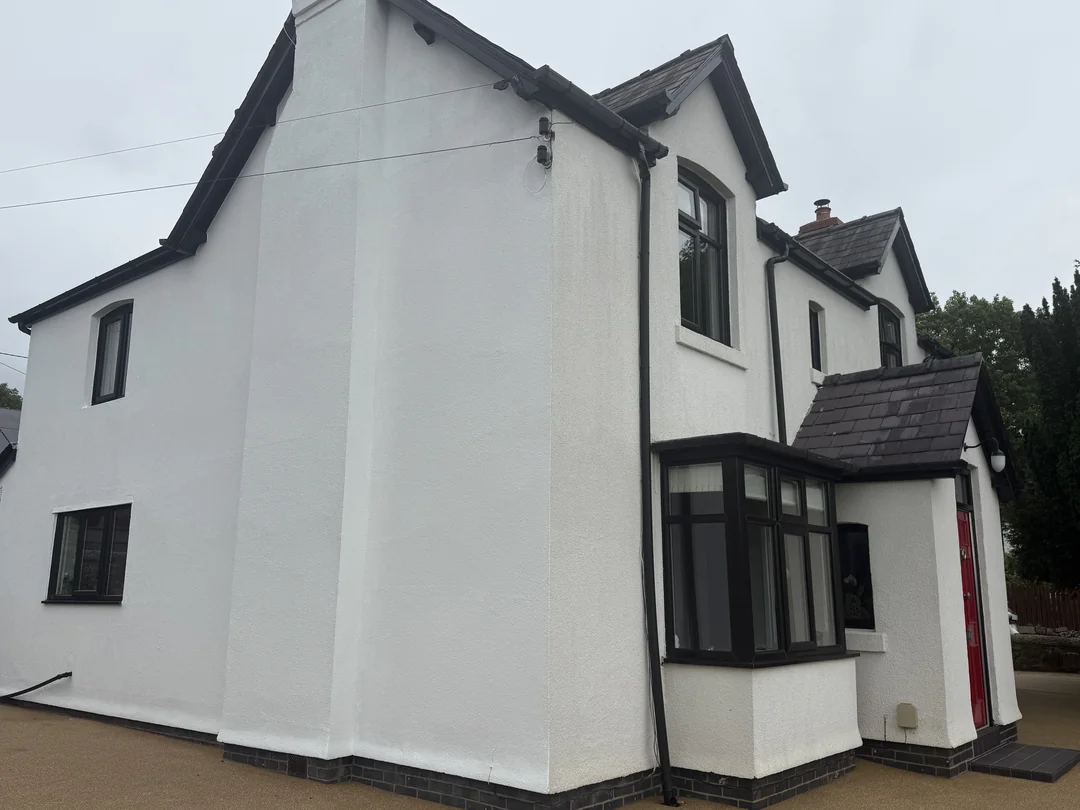 White rendered exterior with dark painted trim and window surrounds