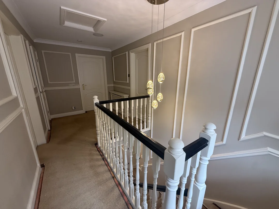 Finished wall mouldings and white balustrade with a black handrail on the Whitegate landing