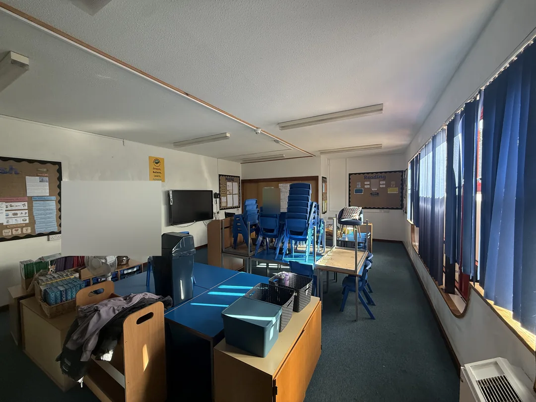 A further completed classroom with light walls and ceiling, retained blue blinds and furniture grouped together.