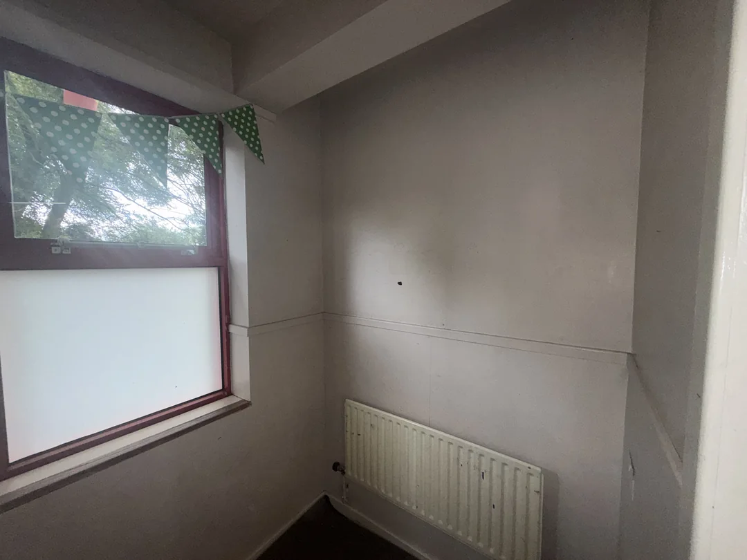 The wall and radiator beside the smaller classroom window before redecoration.
