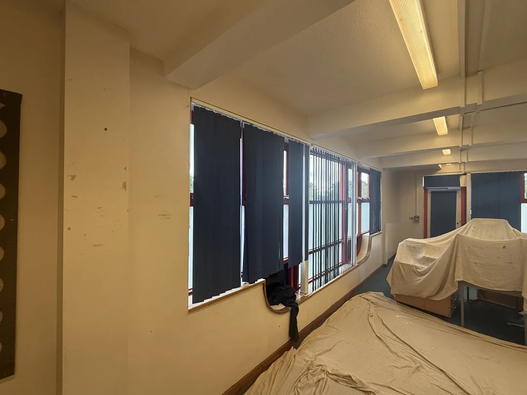 Marked classroom wall beside the retained blue blinds before redecoration.
