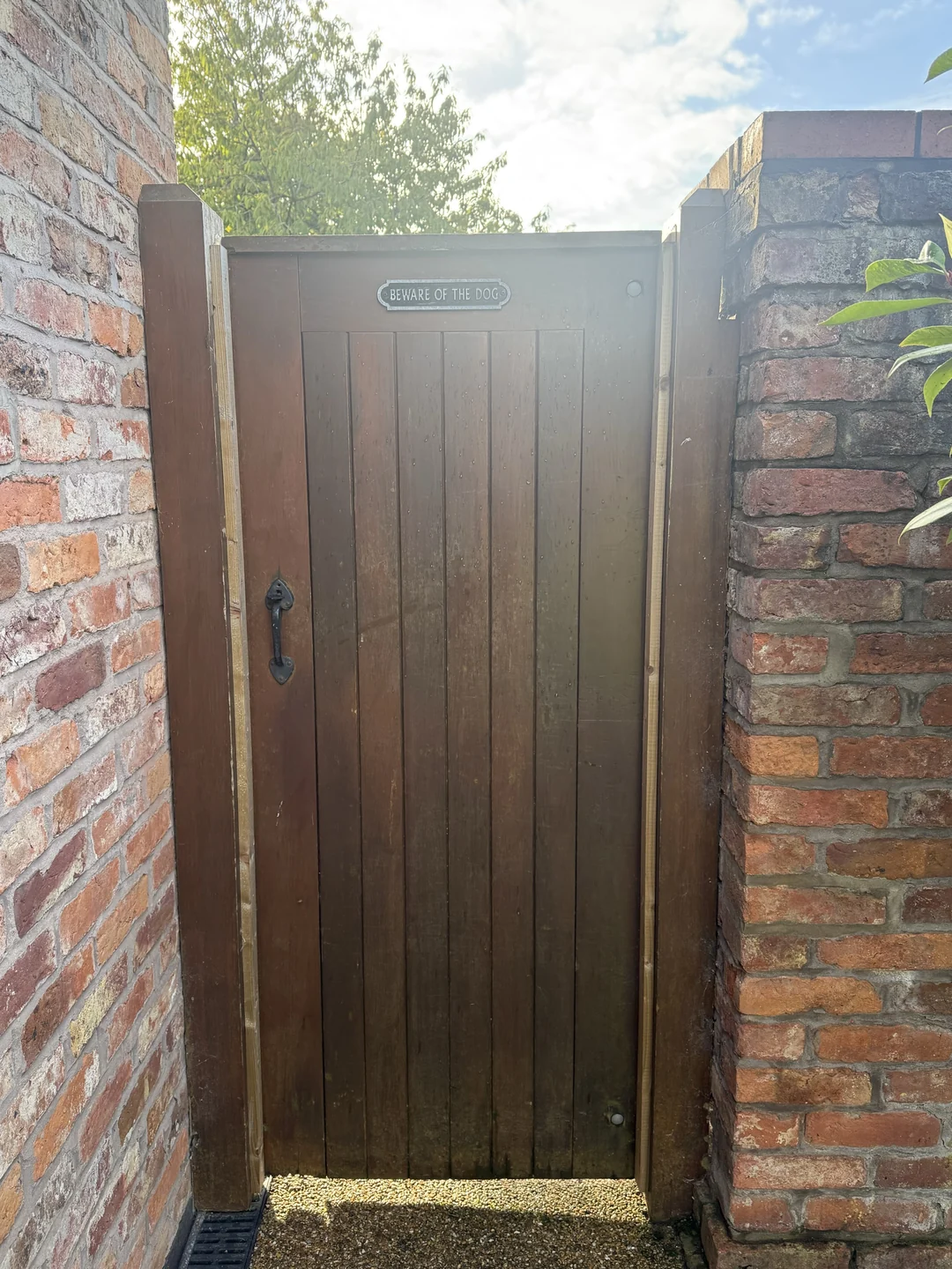The front of the pedestrian gate before repainting, with the existing brown finish and dog sign.