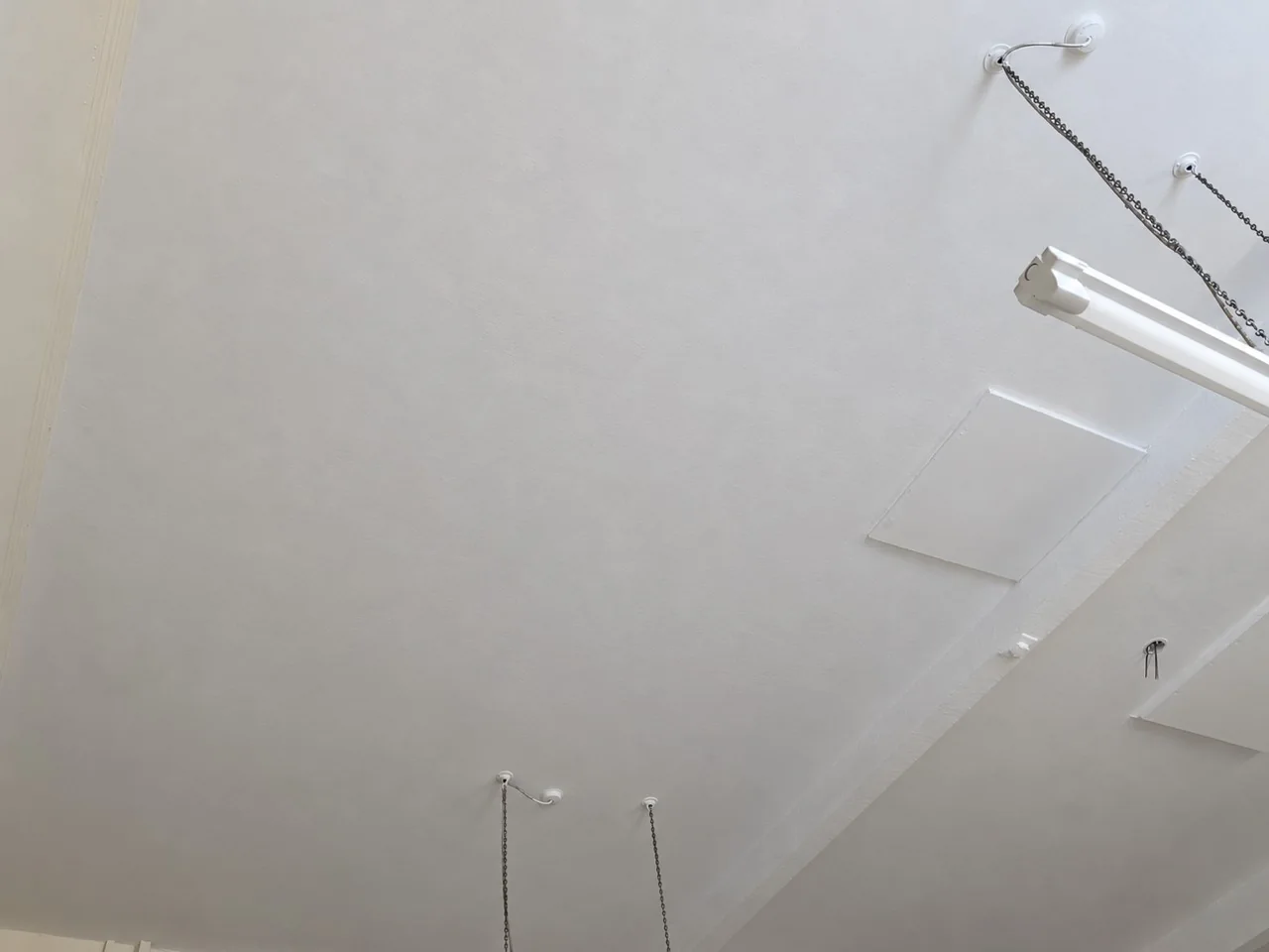 Repainted school ceiling beside the suspended light fitting
