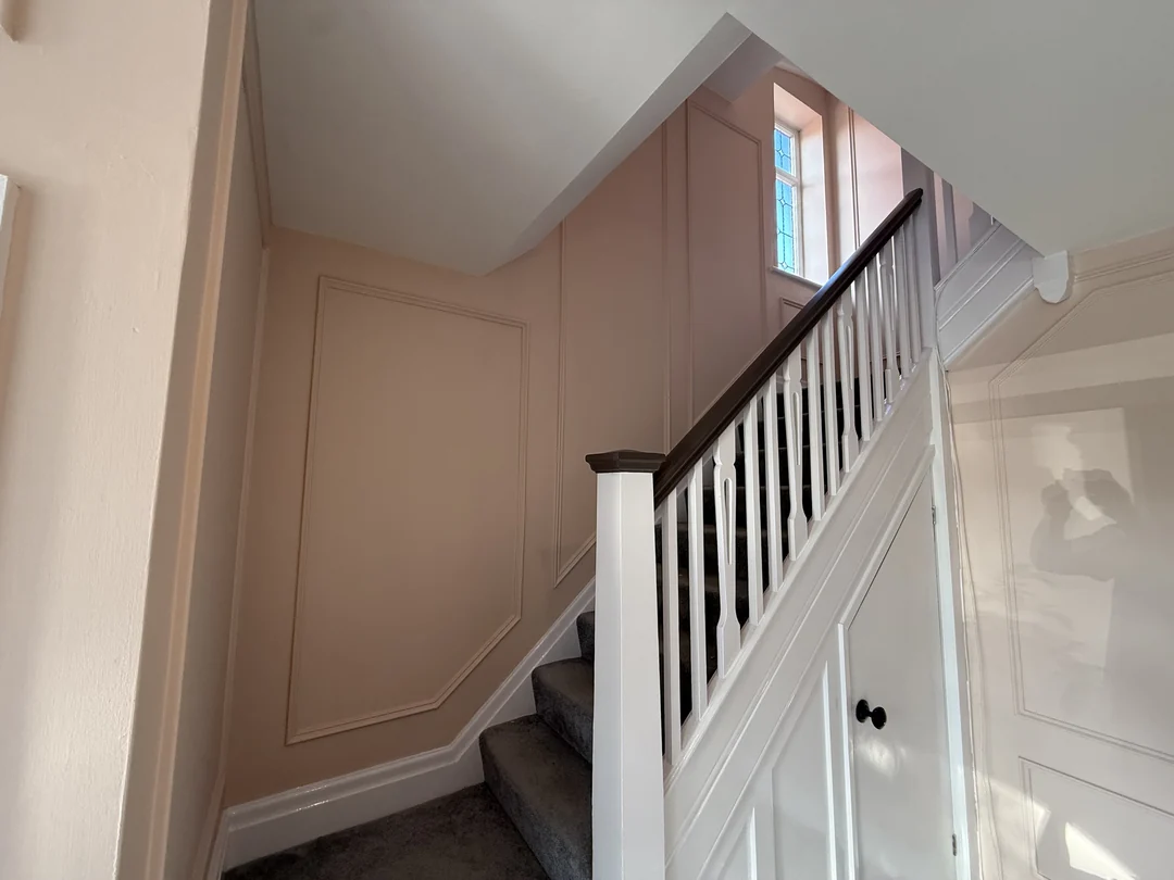 Painted wall beading beside the staircase, with the white balustrade and dark handrail.