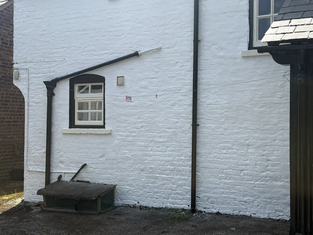 After: the same courtyard wall with its renewed white finish.
