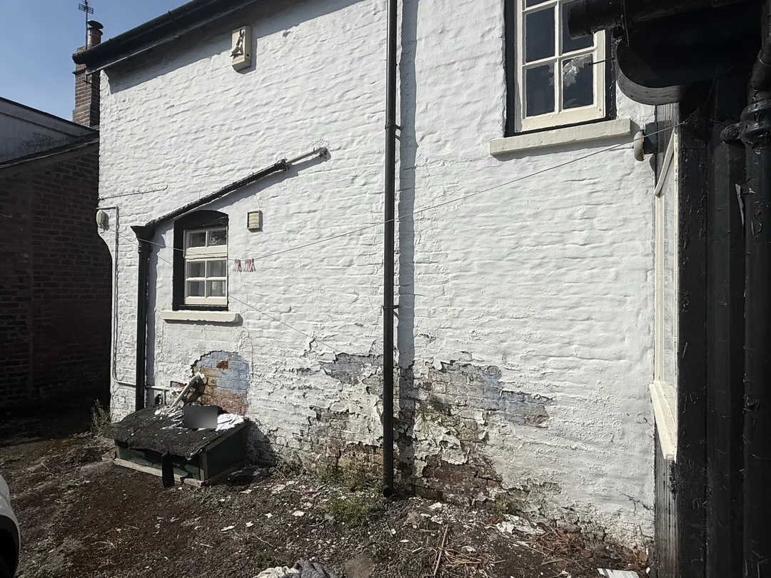 Before: worn and flaking paint on the courtyard wall.