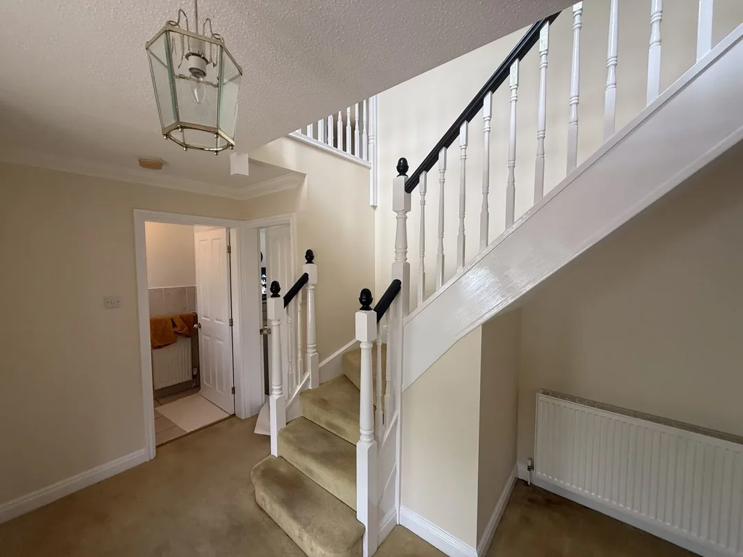 Painted hallway and staircase with a black handrail and white balustrade