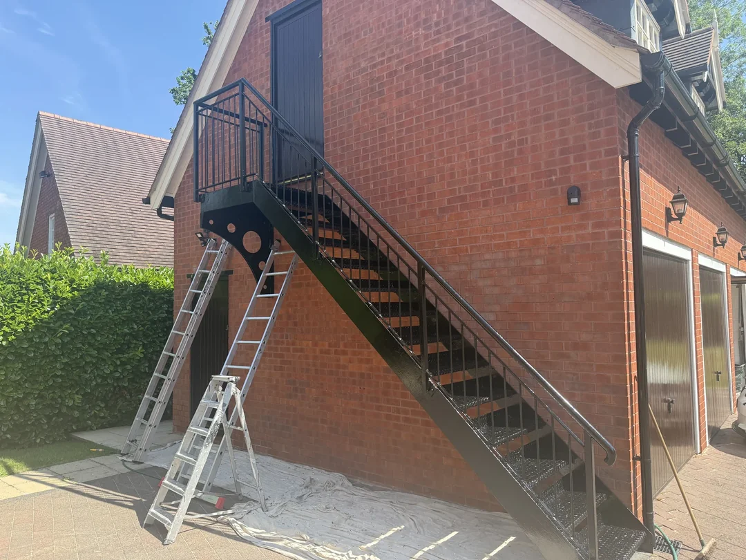The repainted staircase and landing alongside the brick outbuilding.